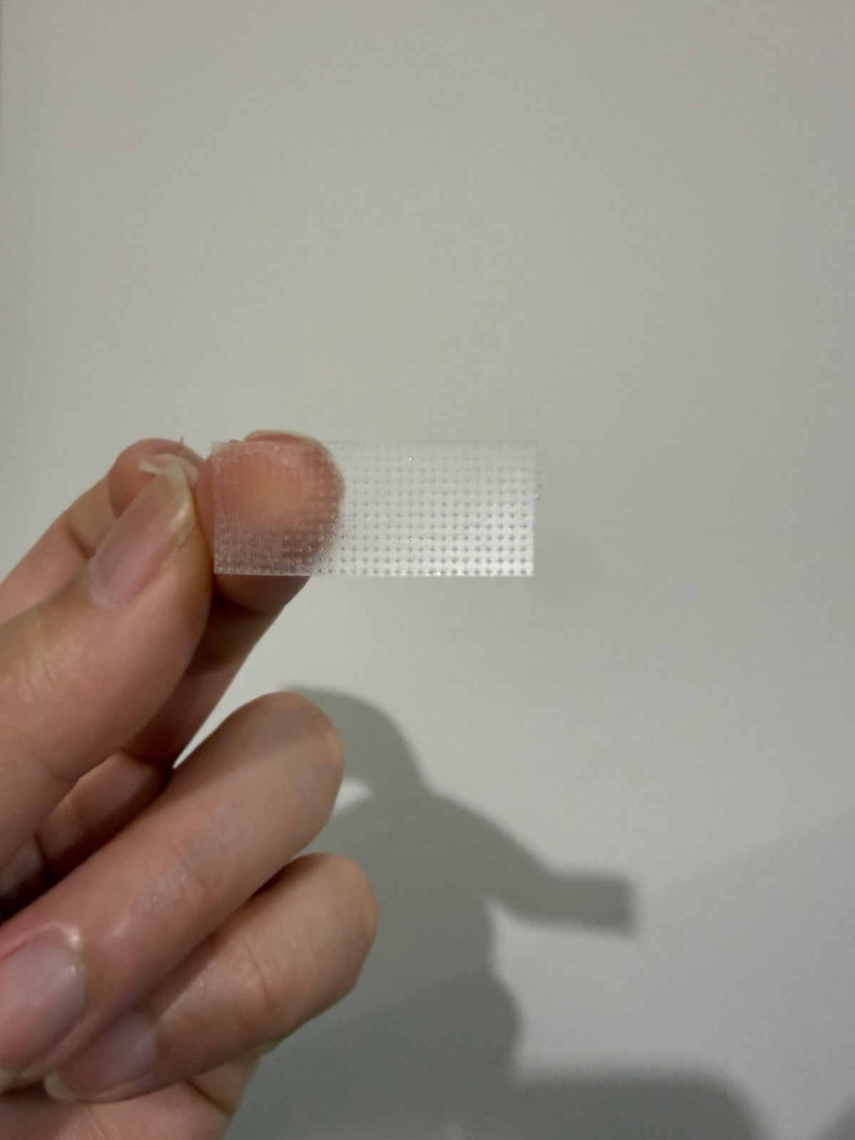 Beige lash-lift tape roll, narrow adhesive strip wound on a dispenser core