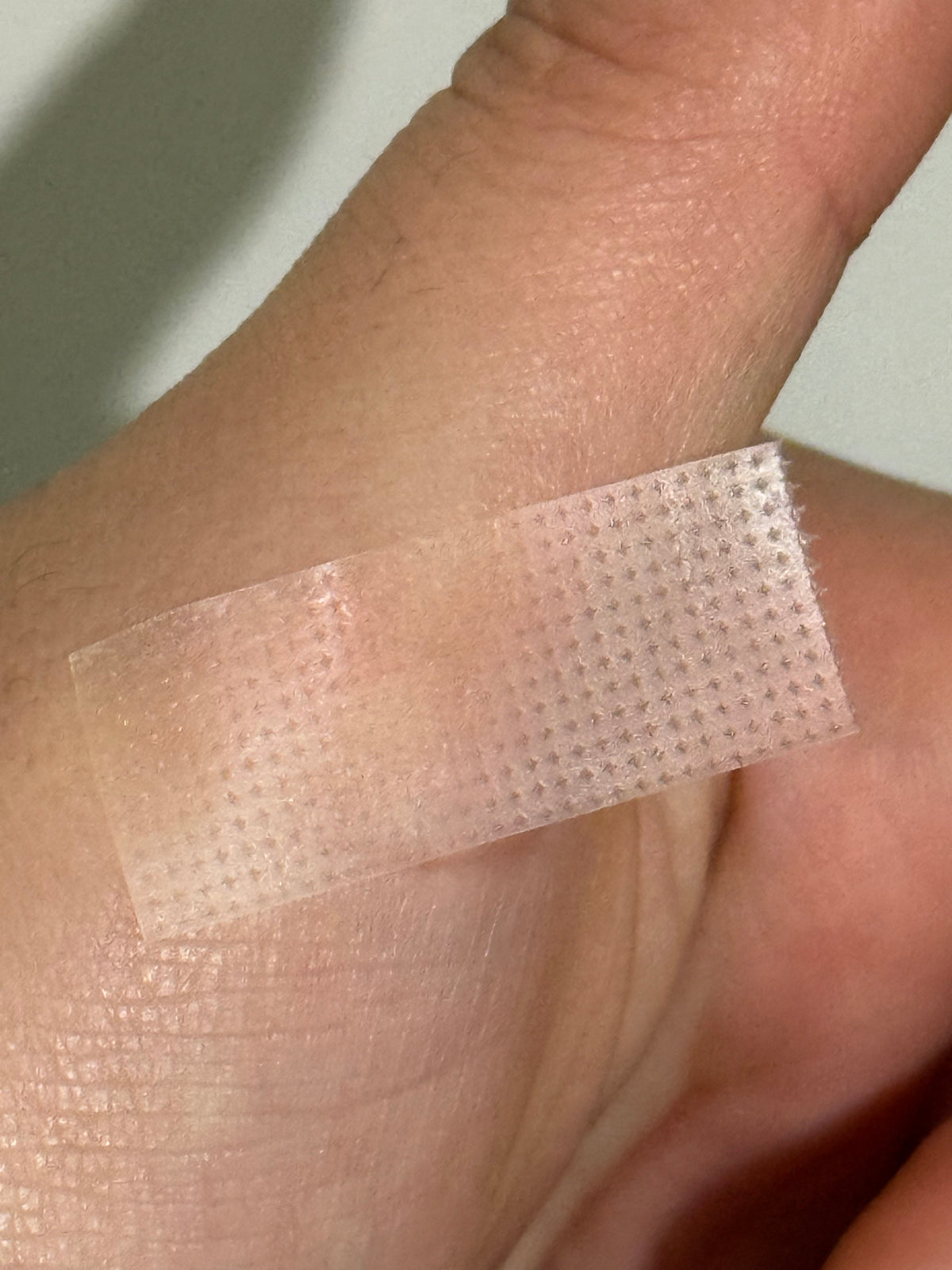 Translucent pink mesh tape strip for lash lifting, adhered on skin
