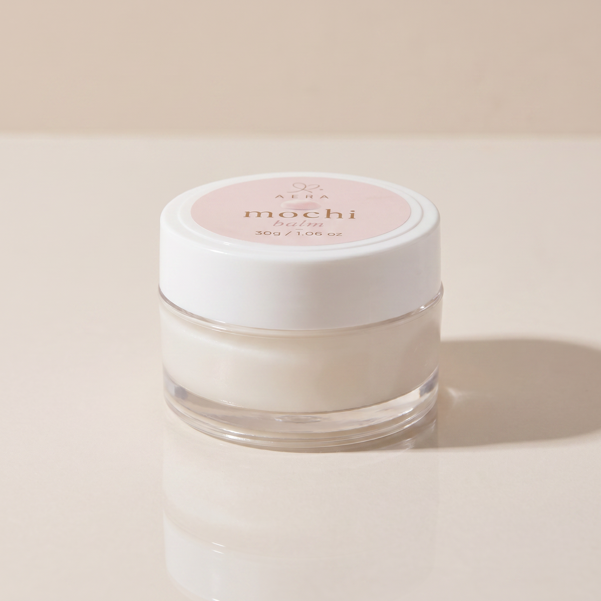 Balm jar with white cap and clear glass base, creamy white formula, front label