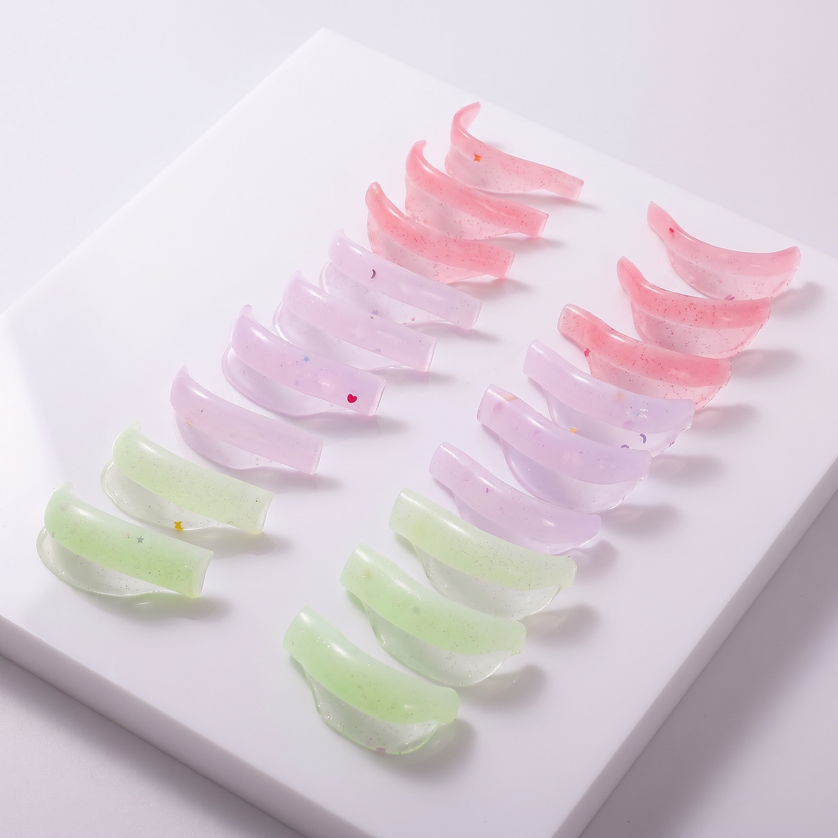 Ascend Shields in pastel pink, lavender and green, arranged on a white board