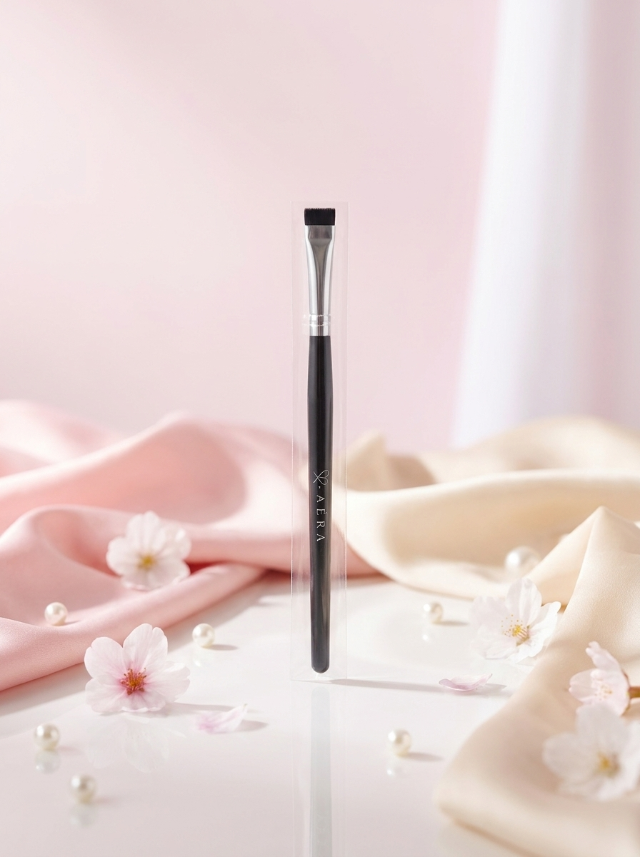 Flat makeup brush with clear handle, white bristles, and black ferrule